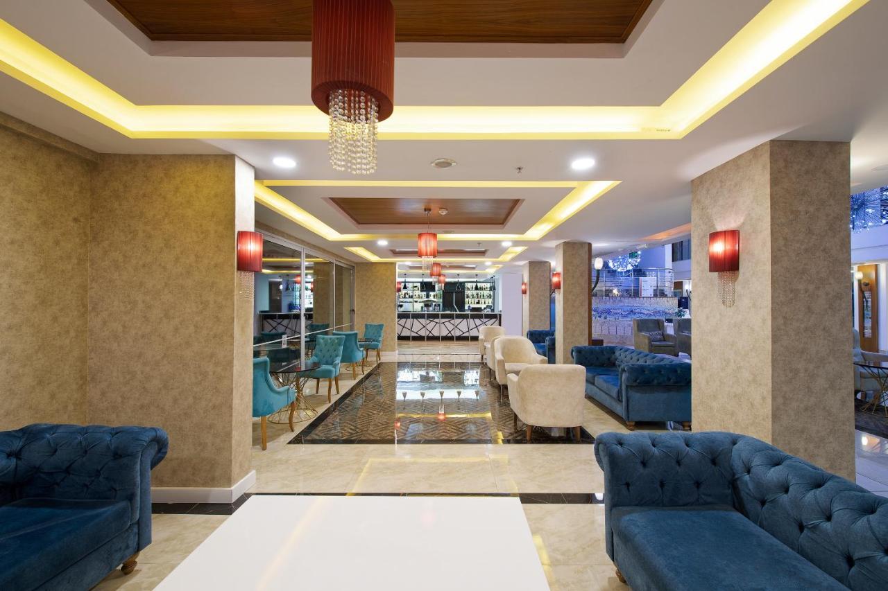 Sealife Family Resort Hotel Antalya Exterior foto The photo depicts a modern and stylish lobby area. It features a combination of elegant furnishings, including blue and cream-colored sofas arranged around white tables. The floor has a shiny, dark tile that contrasts with the light-colored walls. Am
