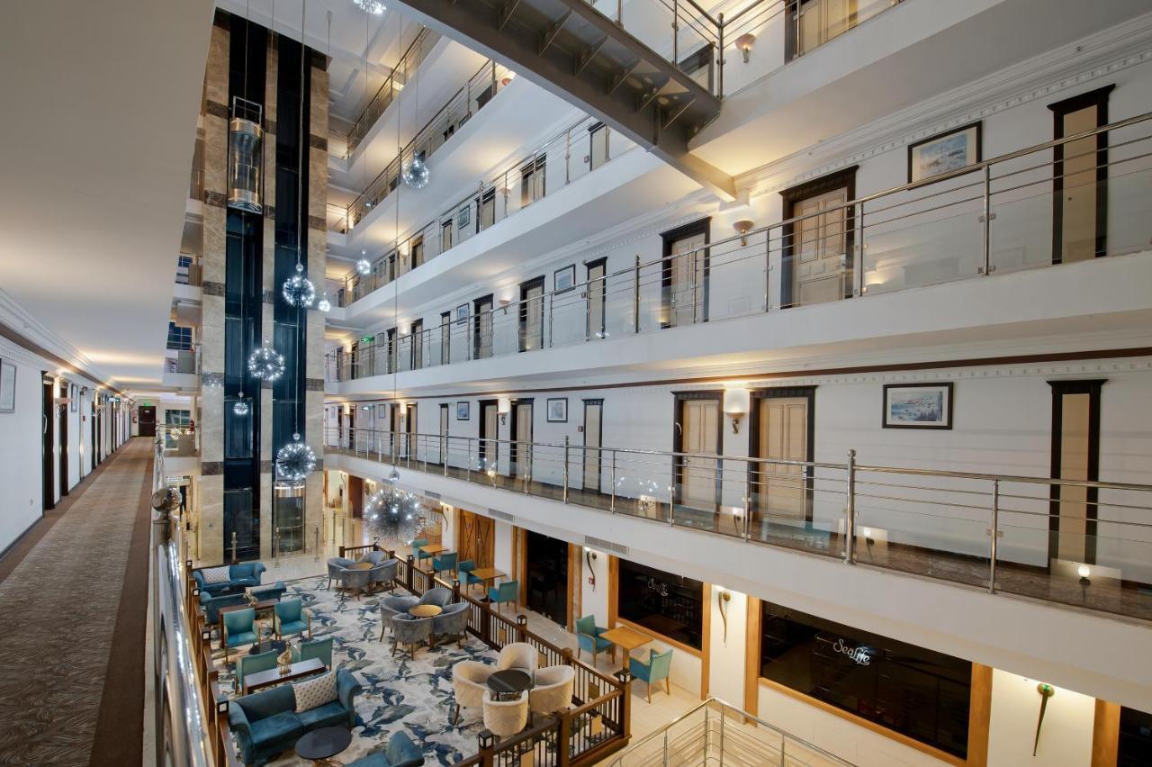 Sealife Family Resort Hotel Antalya Exterior foto The photo shows the interior of a modern hotel or building featuring a multi-level atrium. There are several floors overlooking the central area, with glass railings providing a view of the spaces below. The decor includes stylish seating areas with 