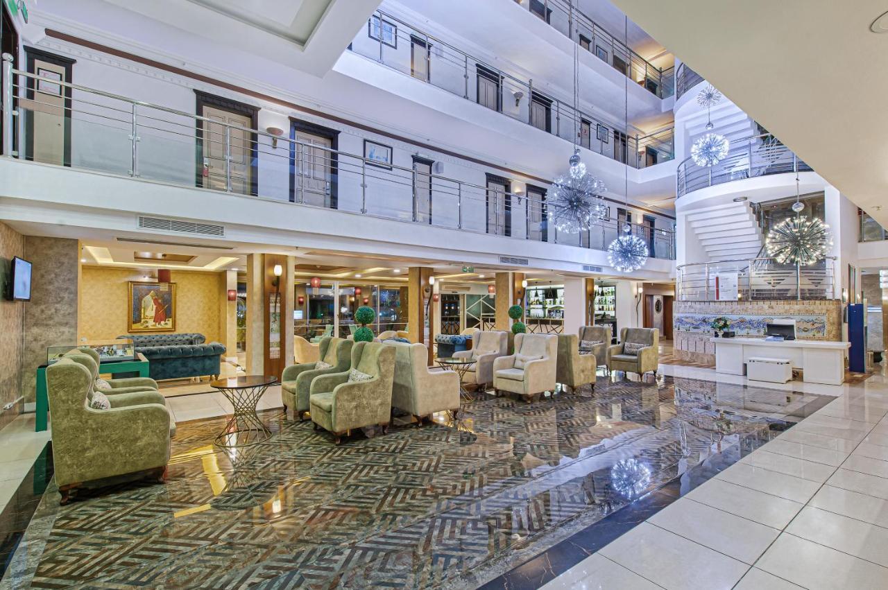 Sealife Family Resort Hotel Antalya Exterior foto The image shows a spacious hotel lobby with a modern and elegant design. The area features a high ceiling with multiple levels, large windows allowing natural light to filter in, and stylish decor elements. There are comfortable seating arrangements 