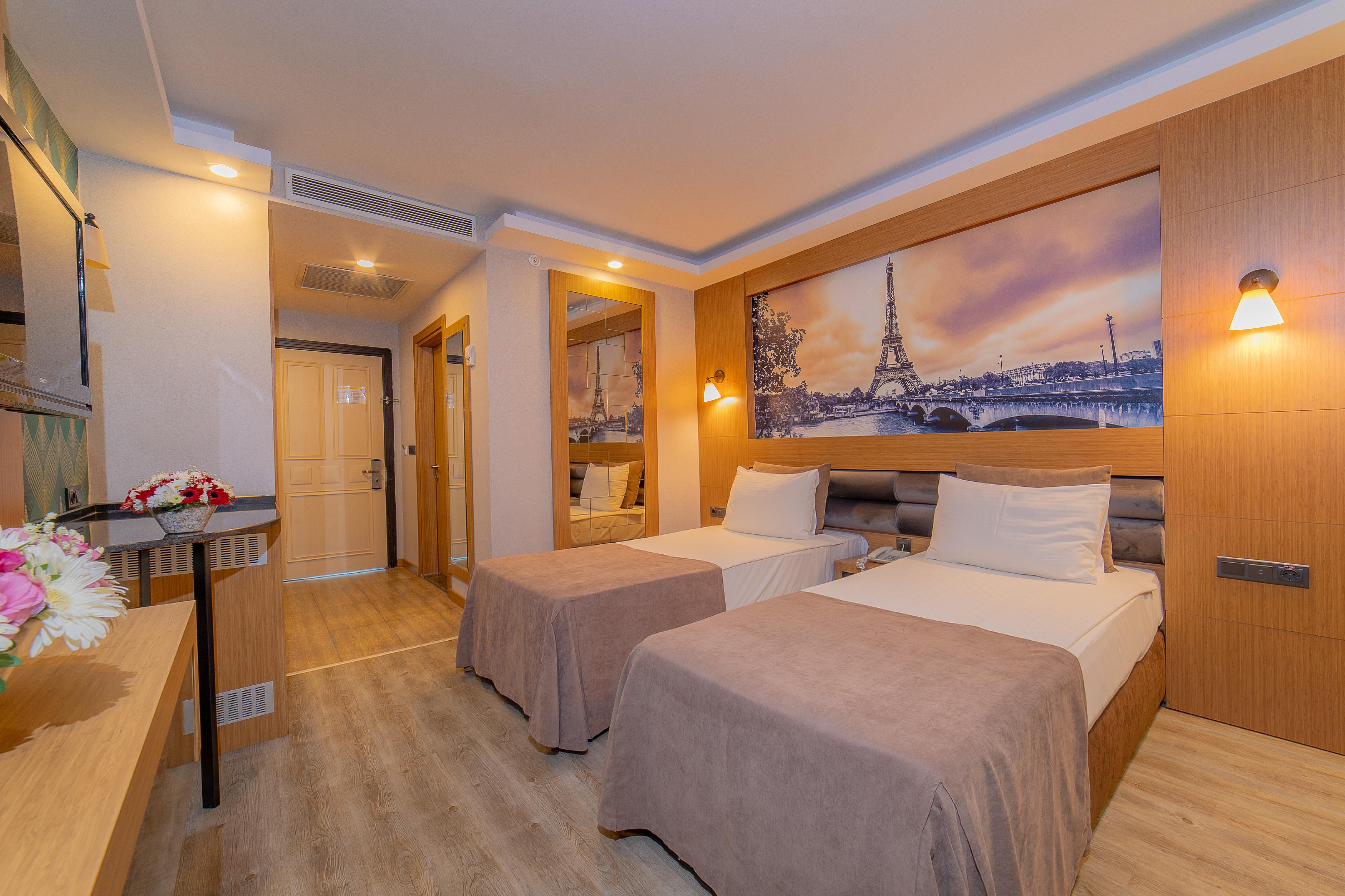 Sealife Family Resort Hotel Antalya Exterior foto The photo depicts a modern hotel room featuring two single beds with light-colored bedspreads. The room has a warm and inviting ambiance, enhanced by the soft lighting. A large mirror is mounted on one wall, reflecting part of the room. Above the bed
