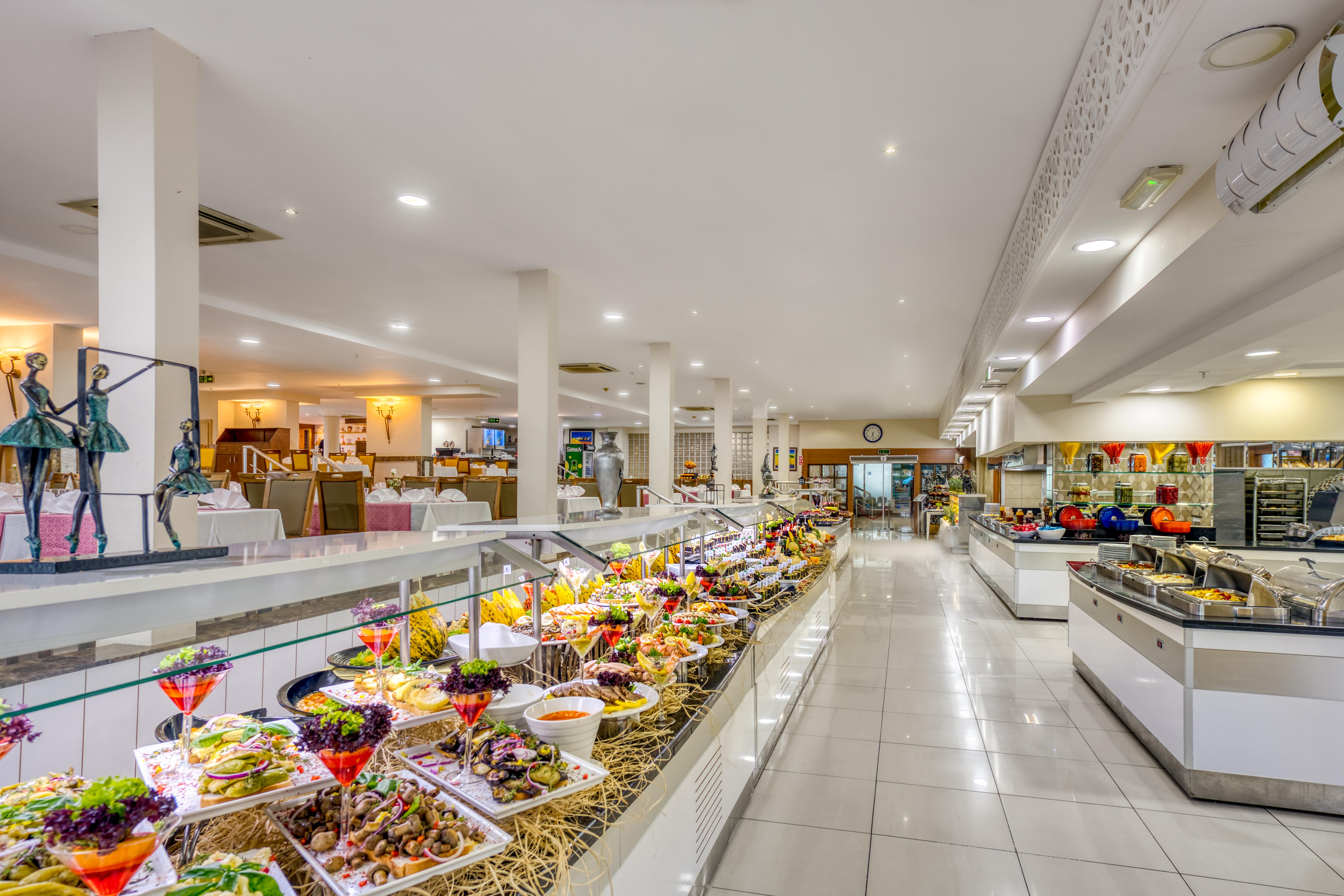 Sealife Family Resort Hotel Antalya Exterior foto The photo shows a spacious dining area, likely a buffet or restaurant, featuring a wide array of colorful food presentations. There are multiple serving stations with neatly arranged dishes, including a variety of salads, appetizers, and desserts. Th