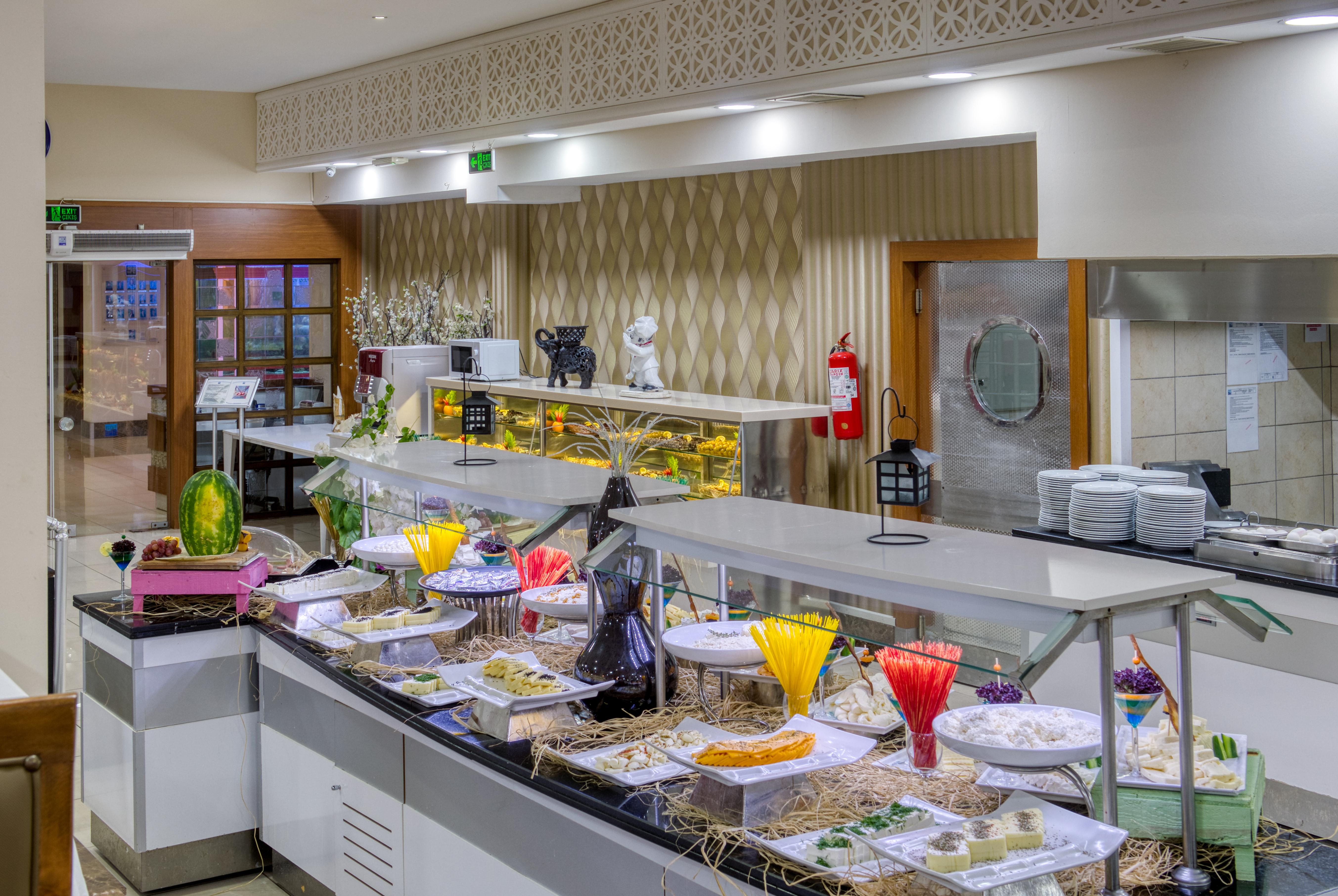 Sealife Family Resort Hotel Antalya Exterior foto The image shows a buffet or dining area featuring a variety of colorful dishes and desserts displayed on a long serving counter. It includes decorative plates and containers filled with food items, likely intended for a buffet setup. The overall envi