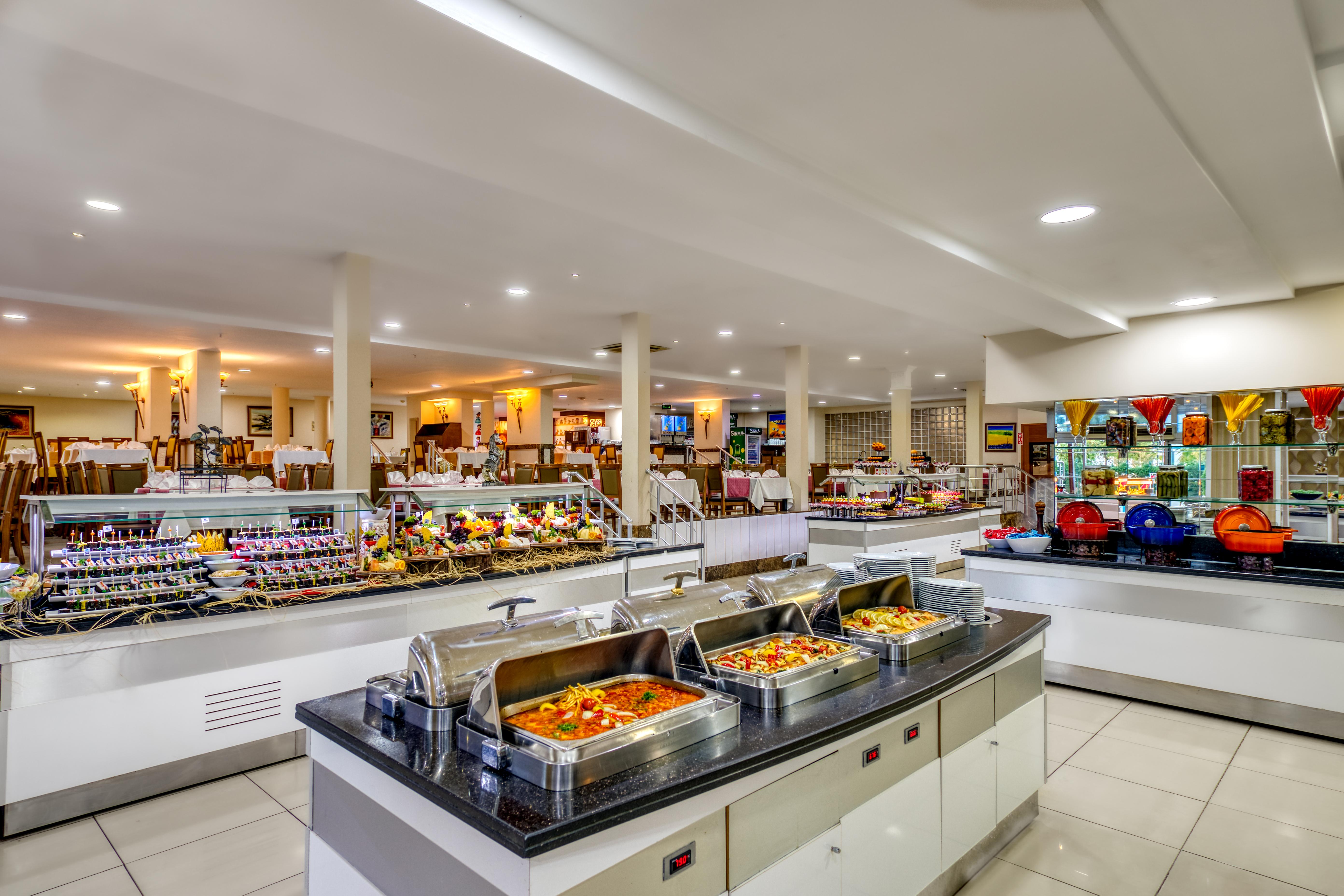 Sealife Family Resort Hotel Antalya Exterior foto The photo shows a spacious buffet area in a restaurant. There are several food stations featuring a variety of dishes. In the foreground, there are chafing dishes that contain warm food, likely offering options like pasta, vegetables, or meats. Behin