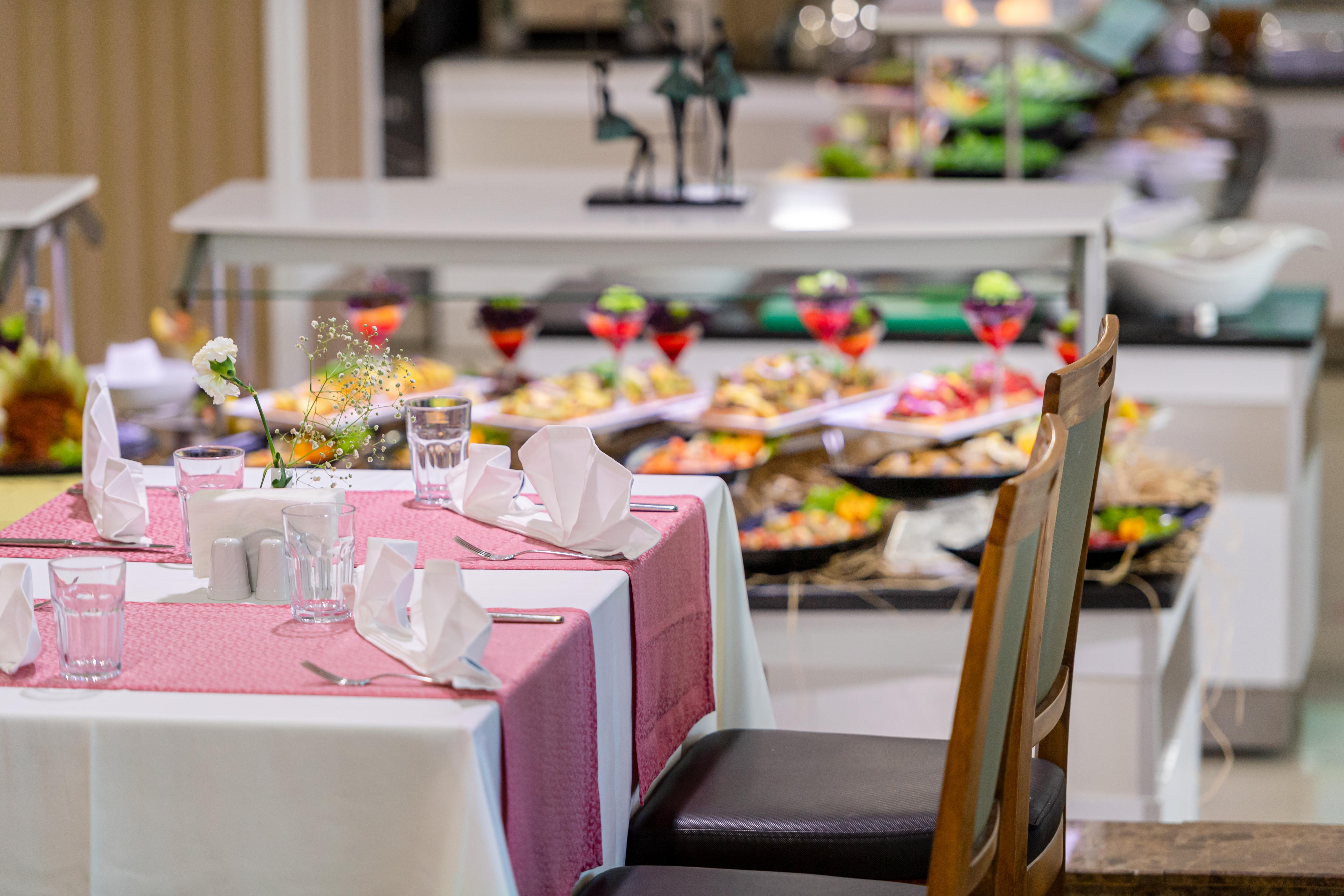 Sealife Family Resort Hotel Antalya Exterior foto The photo features a dining area of a buffet restaurant. In the foreground, there's a neatly set table with a pink tablecloth, white napkins, and glasses. In the background, a variety of dishes is displayed on a buffet table, showcasing an assortment