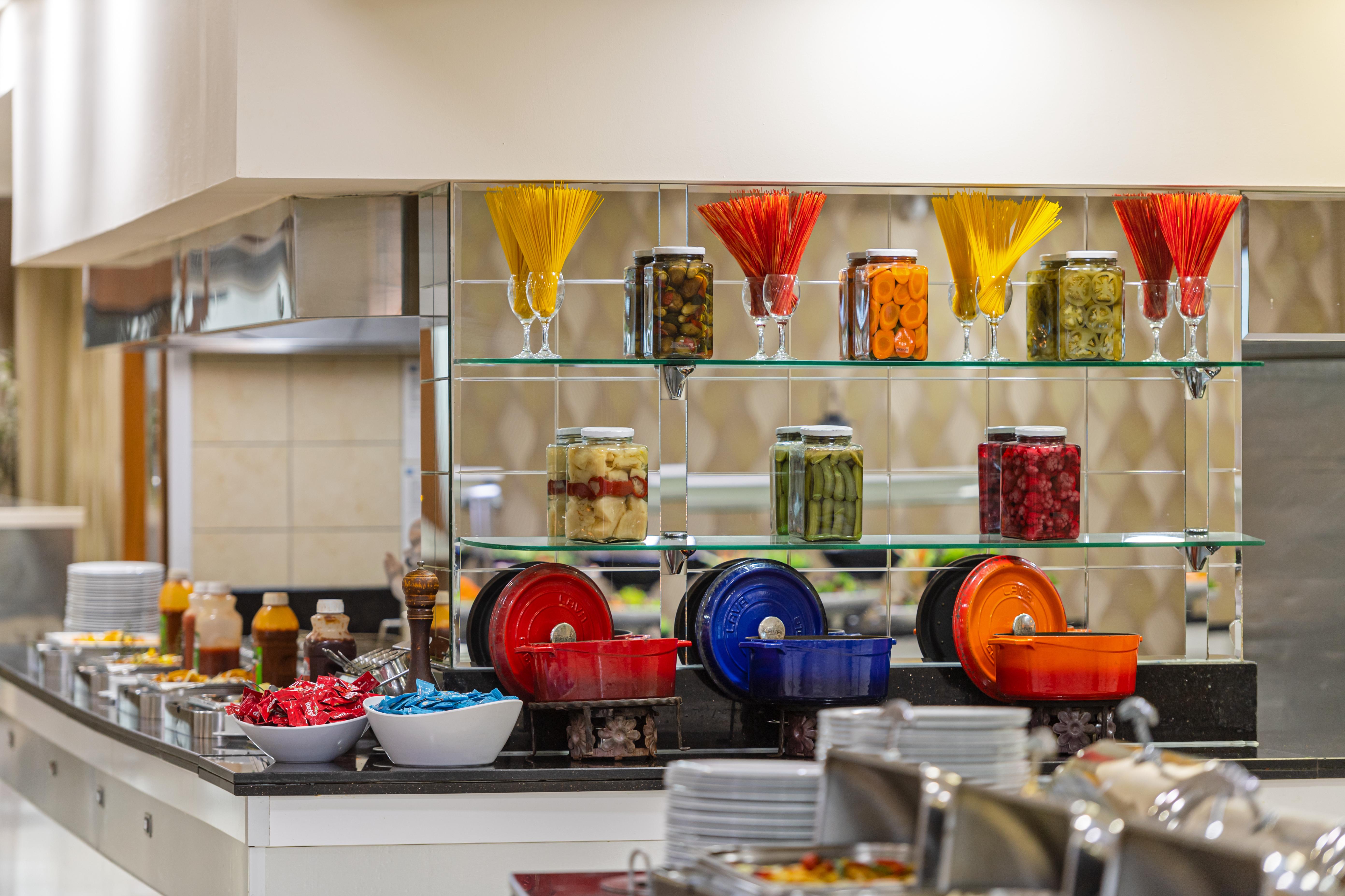 Sealife Family Resort Hotel Antalya Exterior foto The photo shows a buffet-style food display with a modern and organized arrangement. There are several jars filled with various colorful ingredients, including pasta and preserved fruits or vegetables, displayed on glass shelves. Below, there are bow