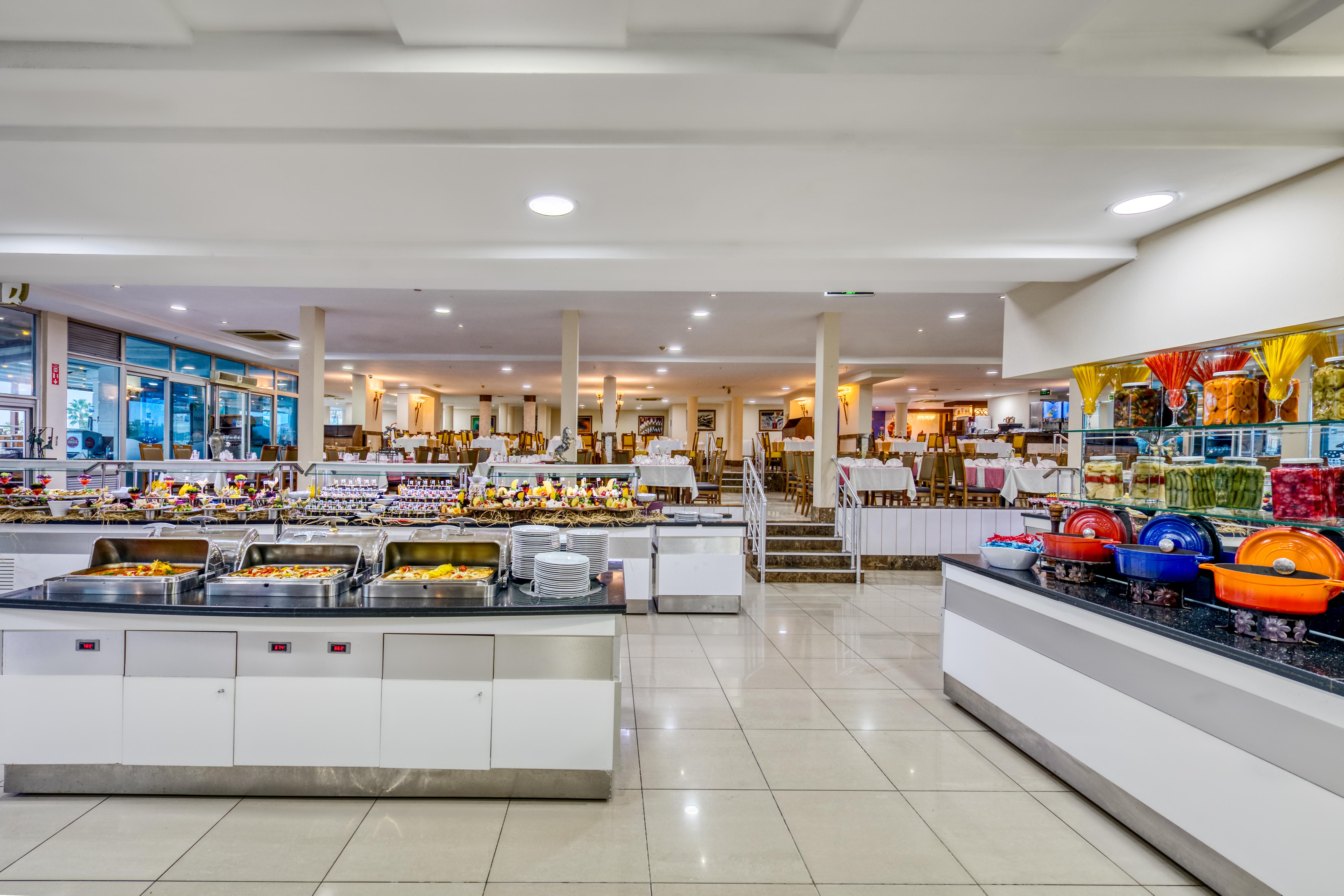 Sealife Family Resort Hotel Antalya Exterior foto The photo depicts a spacious buffet dining area featuring several food stations. There are multiple serving counters filled with a variety of dishes, showcasing an array of foods typically found in a buffet setting. The space is well-lit, with a mode
