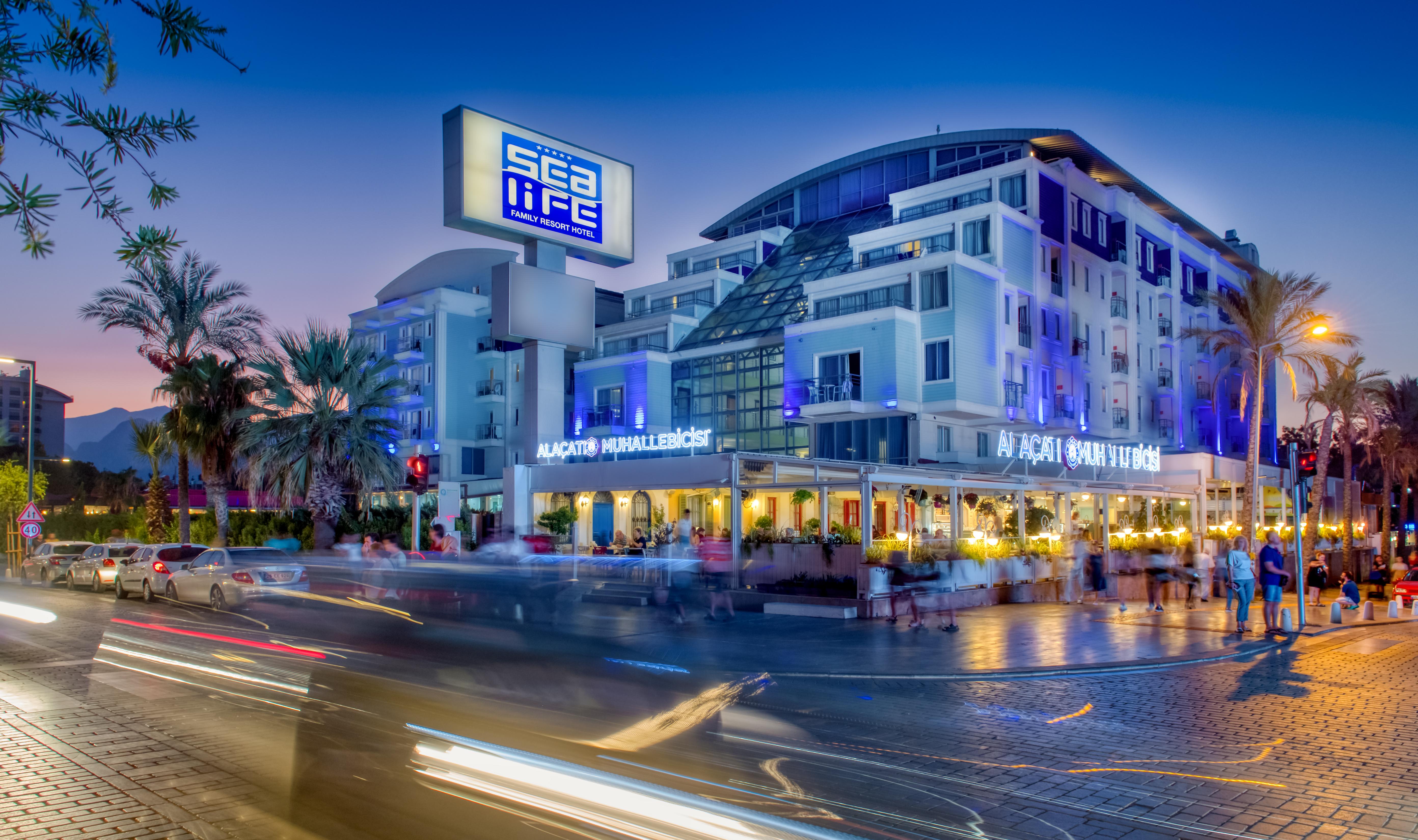 Sealife Family Resort Hotel Antalya Exterior foto The photo shows a modern building with a prominent sign that reads "Sea Life." The structure has multiple stories and a sleek, contemporary design, featuring large windows. In front of the building, there appears to be a restaurant with outdoor seati