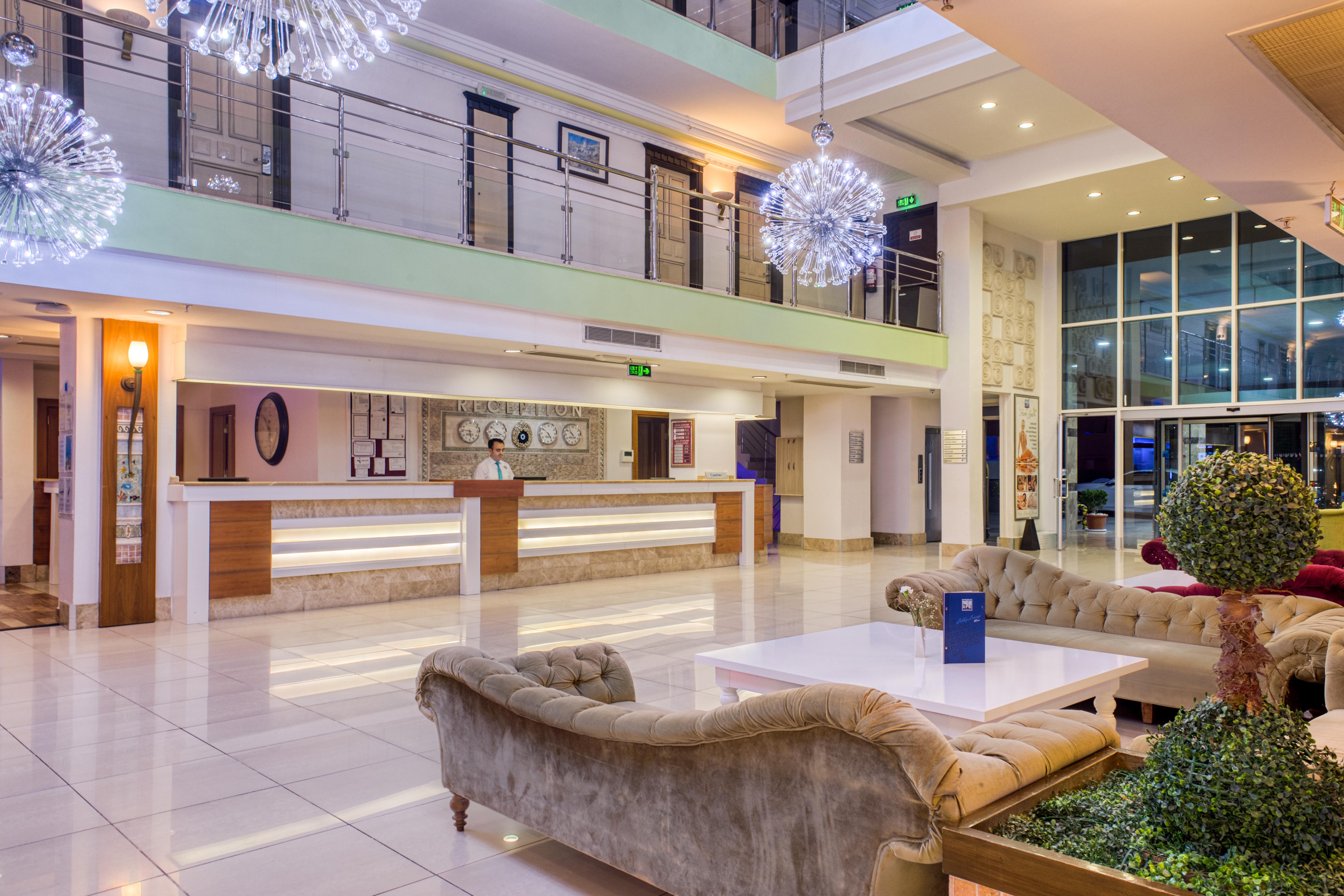 Sealife Family Resort Hotel Antalya Exterior foto The photo depicts a modern hotel lobby. The space features a spacious and stylish design with large windows allowing natural light to enter. There is a reception desk in the background, along with some decorative elements on the walls. The seating ar