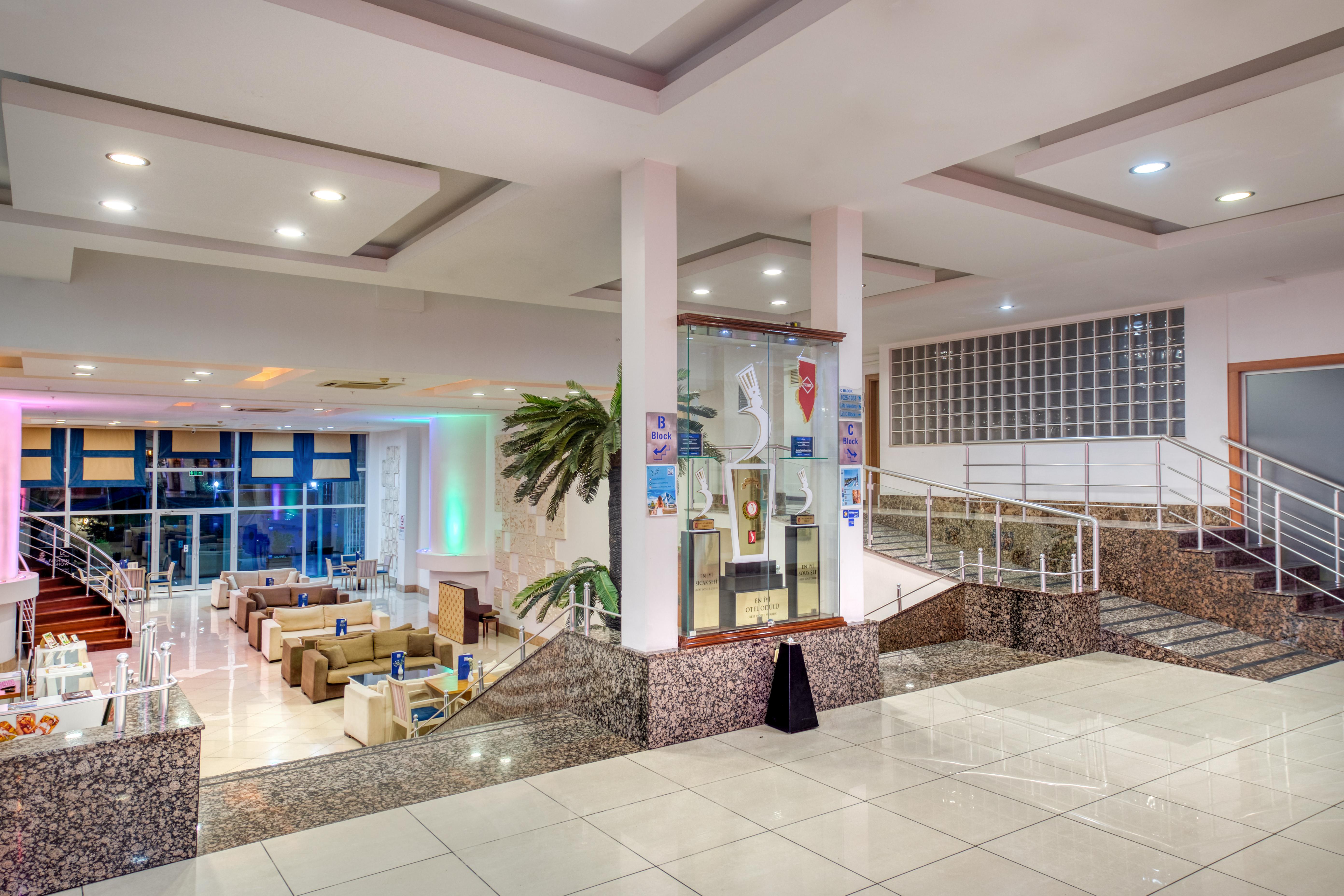 Sealife Family Resort Hotel Antalya Exterior foto The photo shows a spacious indoor area, likely a hotel or a public building, featuring a modern design. There are several seating arrangements with comfortable couches and chairs visible in the background. The space is well-lit, with ambient lighting