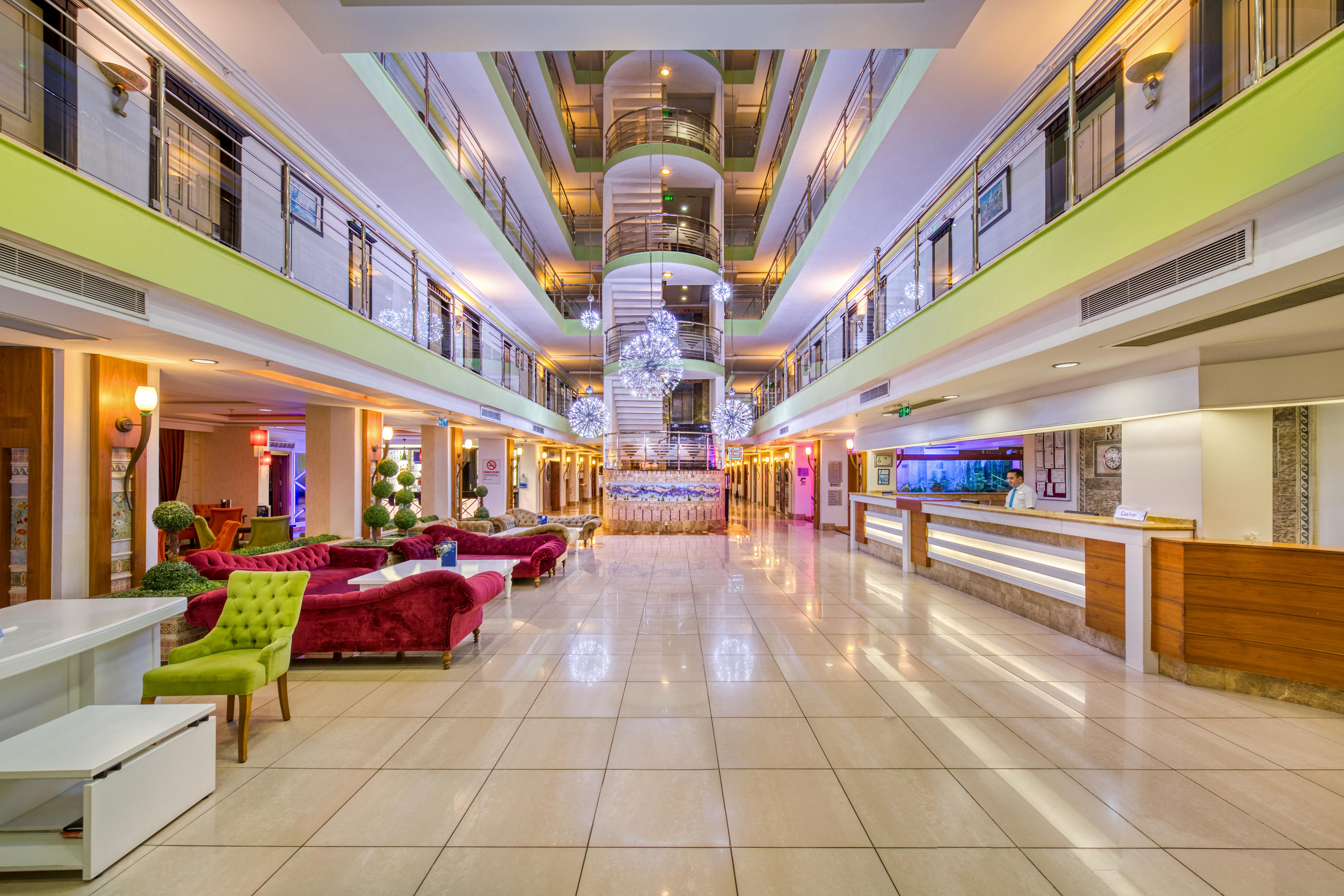 Sealife Family Resort Hotel Antalya Exterior foto The photo shows the interior of a modern hotel lobby. It features a spacious design with a polished tile floor and various seating areas. Elegant sofas in vibrant colors, such as red and green, are arranged tastefully. In the center, there is a strik