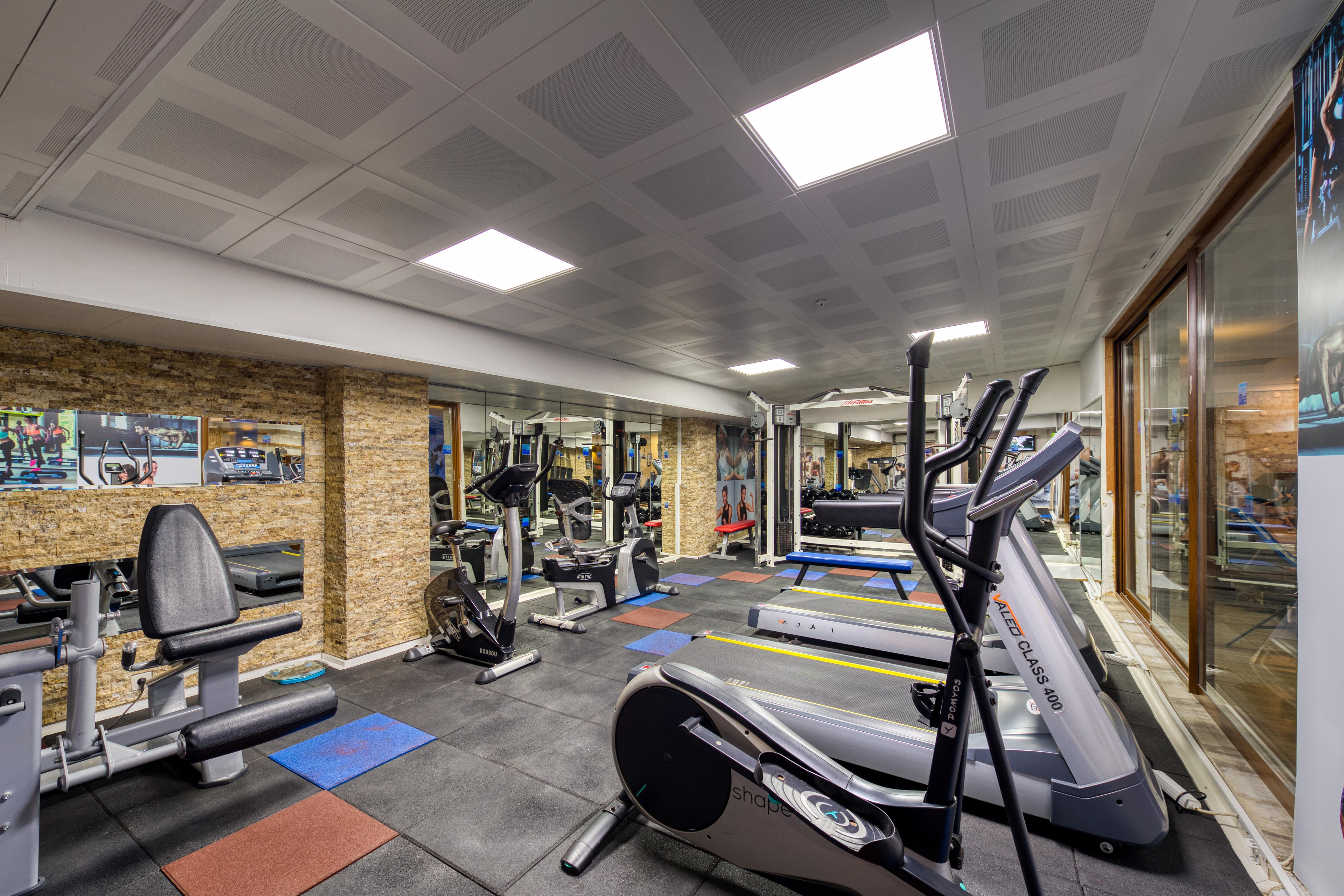 Sealife Family Resort Hotel Antalya Exterior foto The photo shows an indoor gym space equipped with various exercise machines. There are cardio machines like treadmills and an elliptical trainer, along with strength training equipment. The flooring is made of black mats, and there are a few colored 