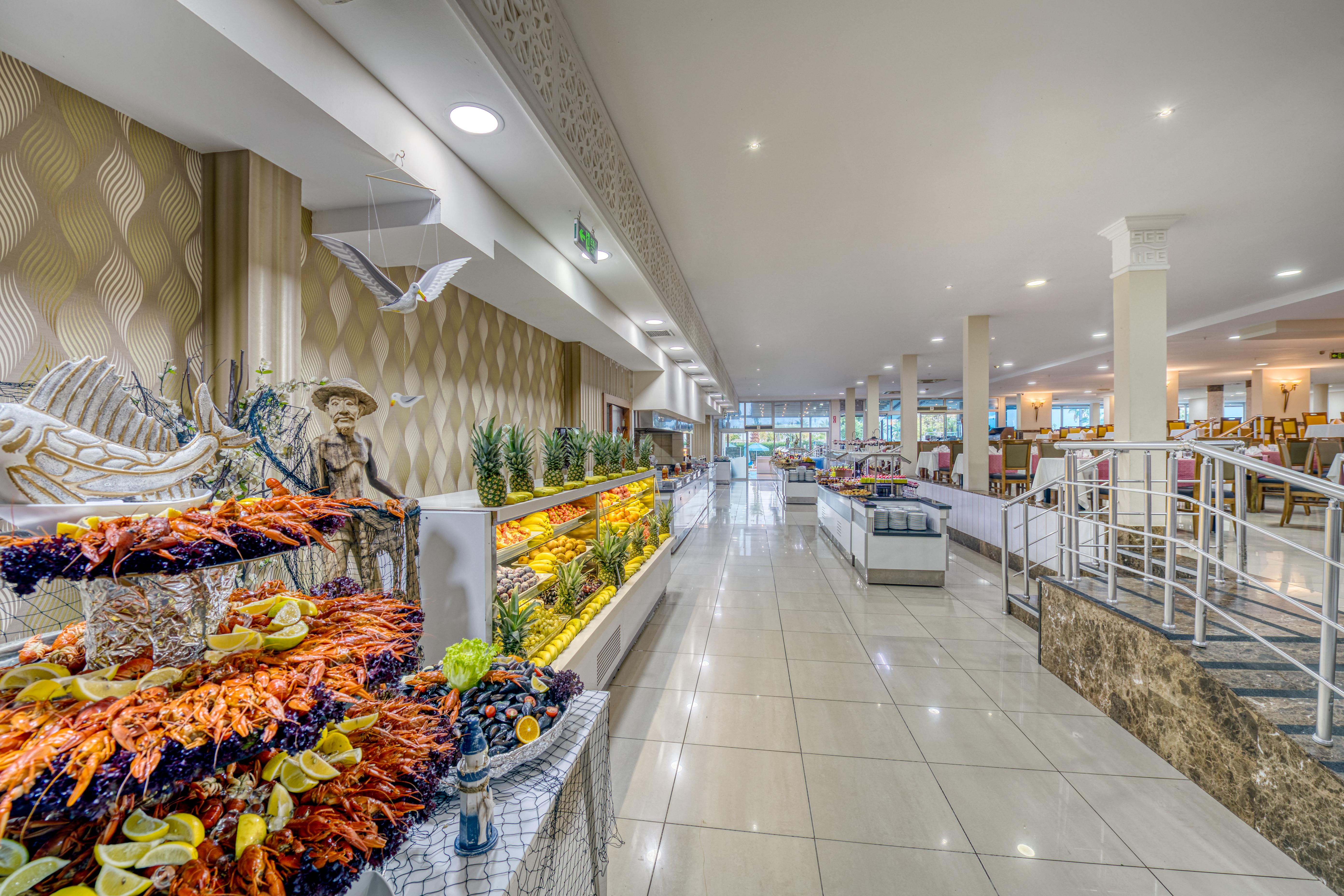 Sealife Family Resort Hotel Antalya Exterior foto The photo shows the interior of a spacious dining area, likely in a restaurant or buffet. The space features a long corridor with glossy tiled floors and bright, well-distributed lighting. On one side, there are decorative displays of seafood, includ