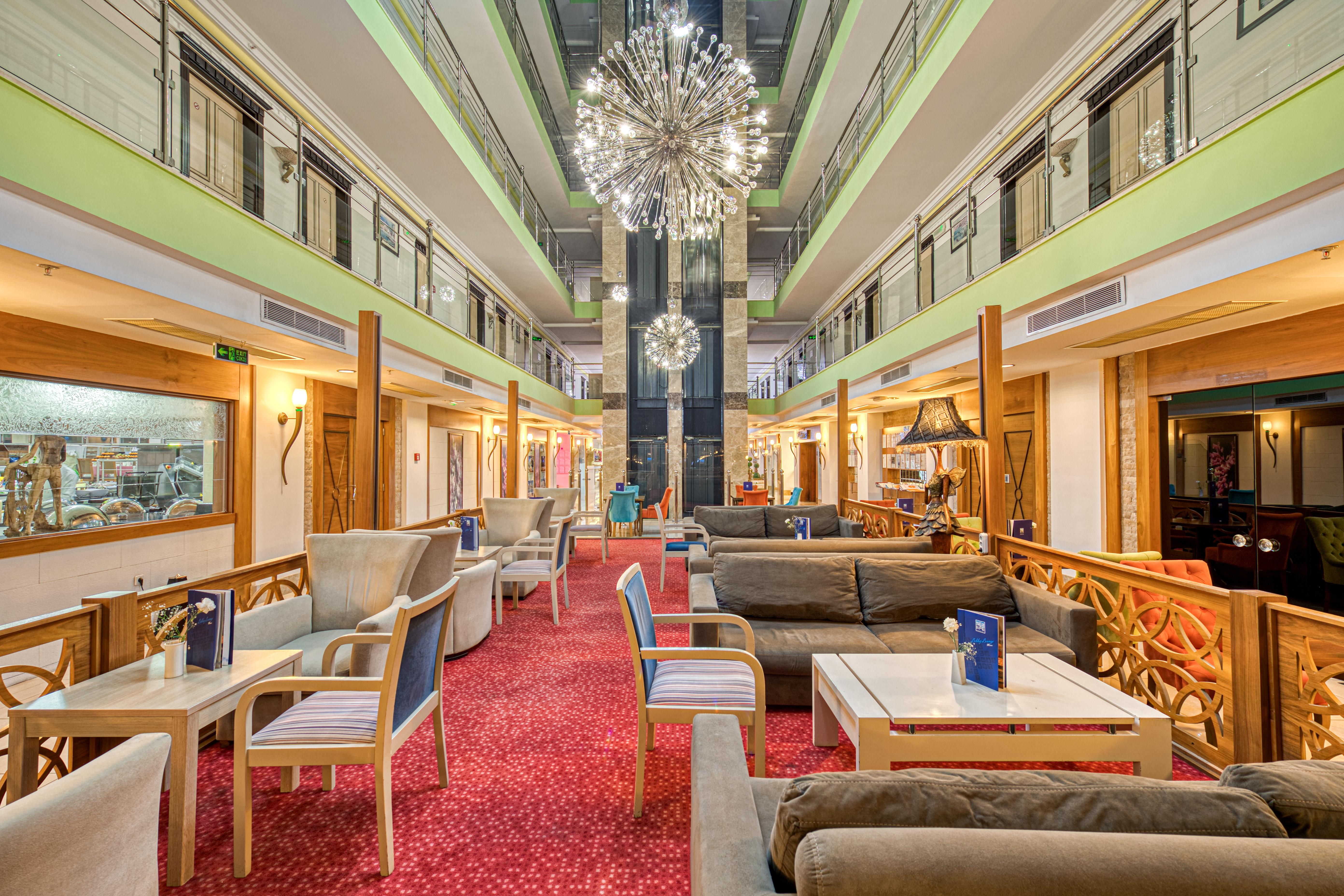 Sealife Family Resort Hotel Antalya Exterior foto The photo shows a spacious and contemporary hotel lobby with a stylish design. There are comfortable seating areas with plush sofas and chairs arranged around small tables. The floor is covered with a rich red carpet, adding warmth to the space. 

Th