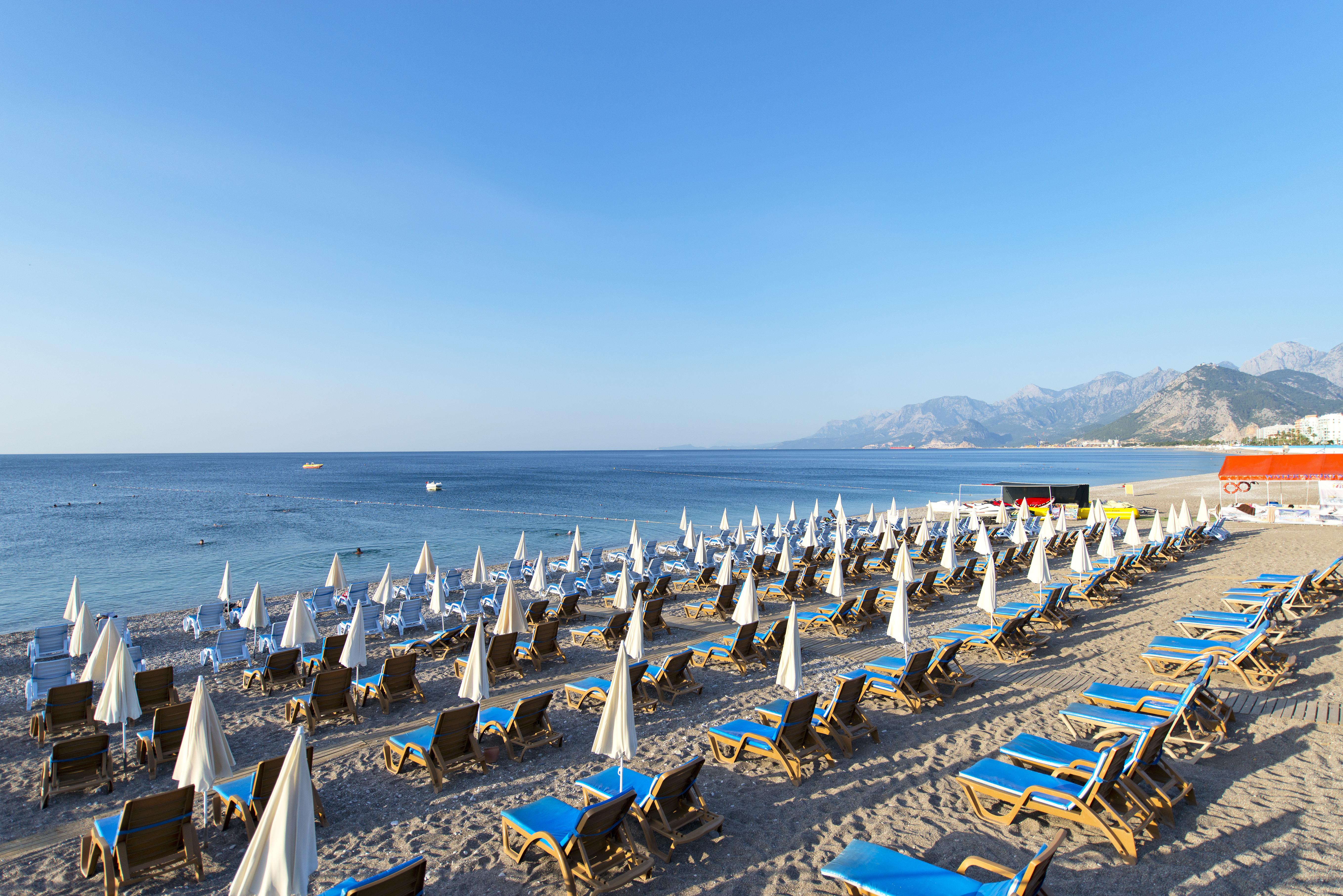 Sealife Family Resort Hotel Antalya Exterior foto The photo depicts a beach scene with numerous sun loungers arranged in rows on the sand, each equipped with white umbrellas. The loungers are primarily blue, creating a vibrant contrast against the sandy beach. In the background, gentle waves can be 