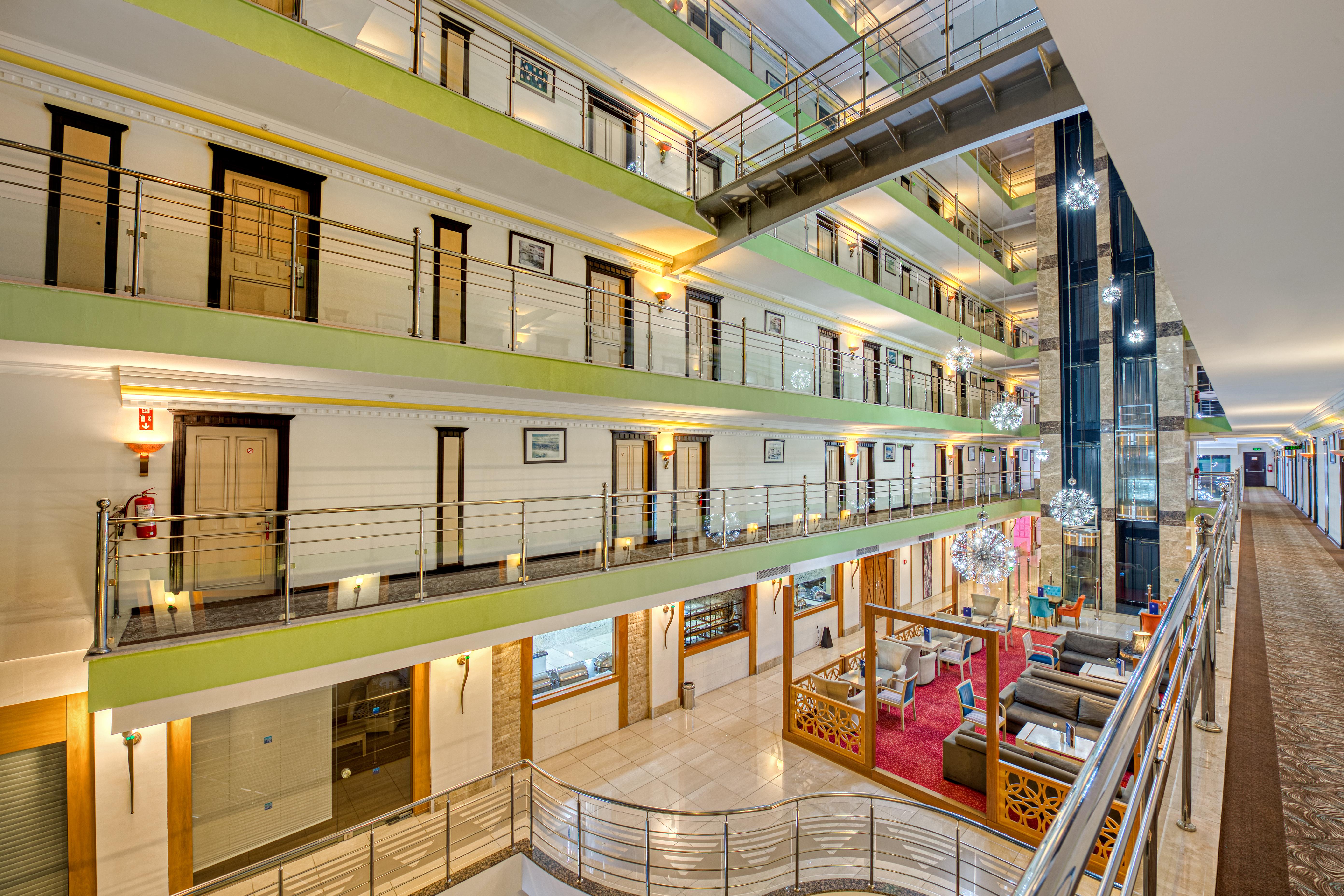 Sealife Family Resort Hotel Antalya Exterior foto The photo depicts the interior of a multi-story hotel or building. There are several levels with open balconies overlooking a central atrium area. The walls are painted in light colors, and there are decorative elements like artwork or plants along t