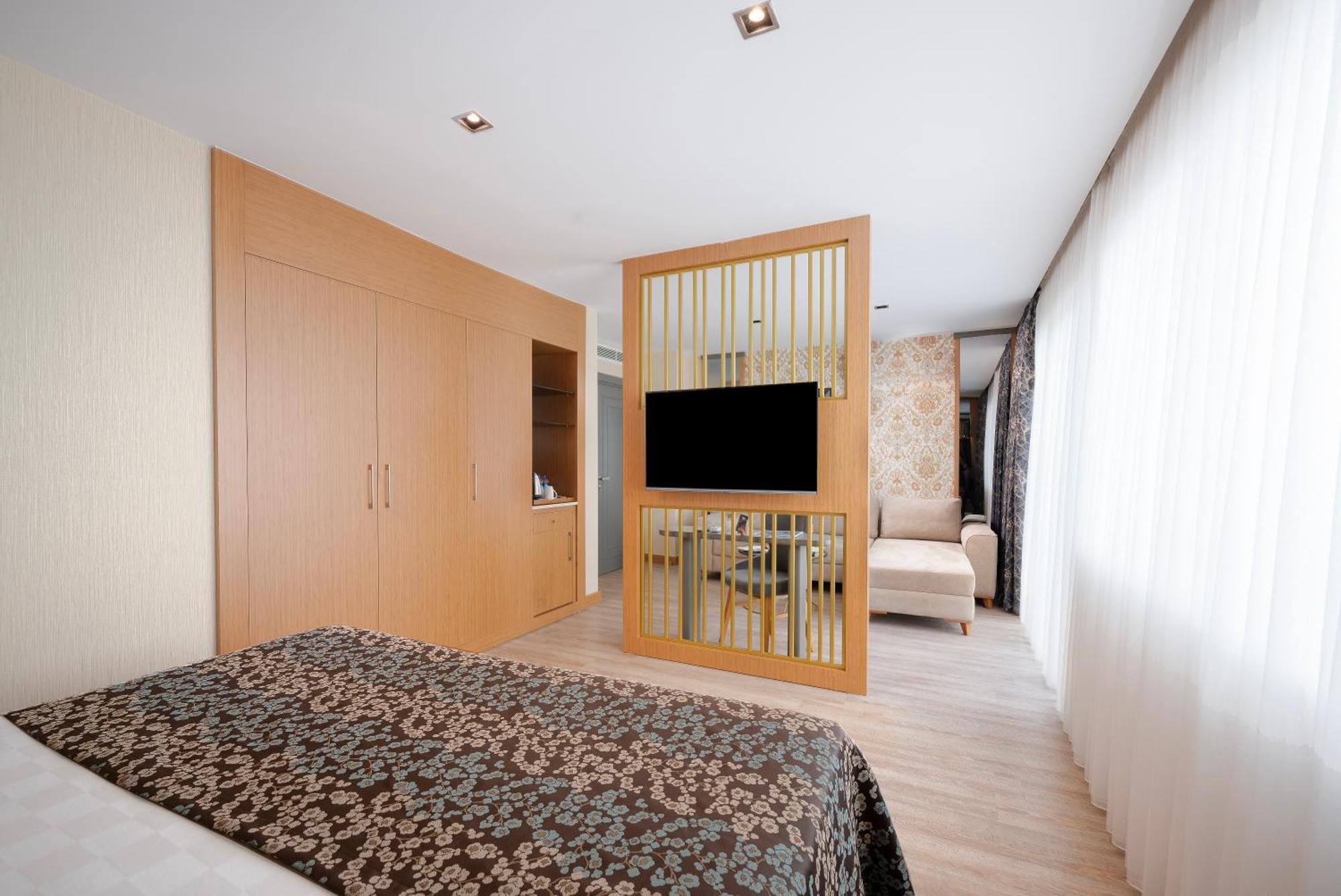 Sealife Family Resort Hotel Antalya Cameră foto The photo depicts a modern hotel room designed with a clean and minimalistic aesthetic. It features a spacious layout with wooden flooring and a combination of light and dark colors. 

On one side, there is a bed with a patterned dark bedspread. The 