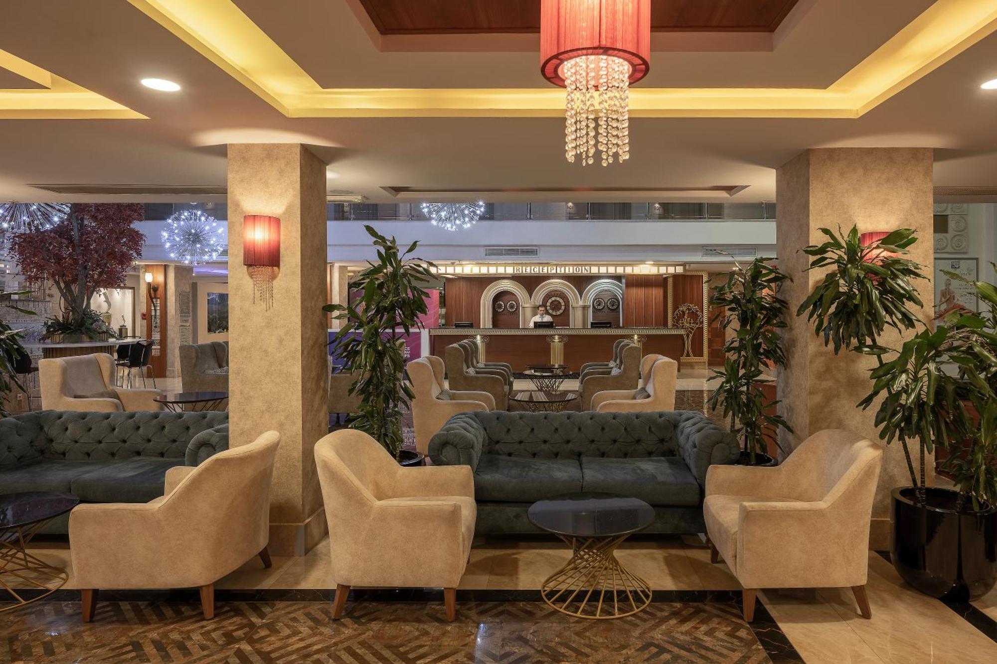 Sealife Family Resort Hotel Antalya Exterior foto The photo shows a stylish and elegant lobby area, featuring comfortable seating arrangements. There are several plush armchairs and a large sofa, which have a mix of light and dark colors. The space is well-lit with ambient lighting, including decora