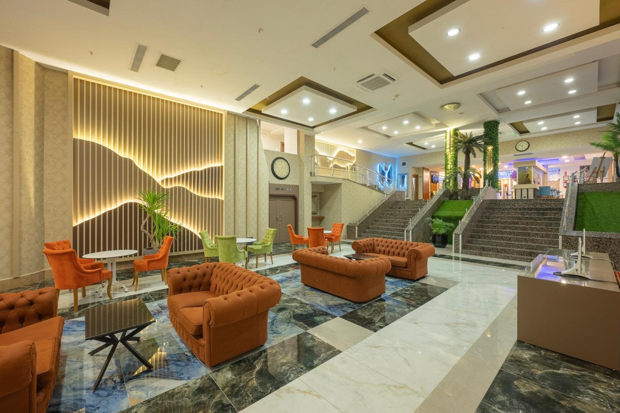 Sealife Family Resort Hotel Antalya Exterior foto The photo depicts a spacious, modern lobby area within a hotel or similar establishment. The floor features a striking design with dark and light marble patterns. There are several comfortable seating arrangements, including orange upholstered sofas 