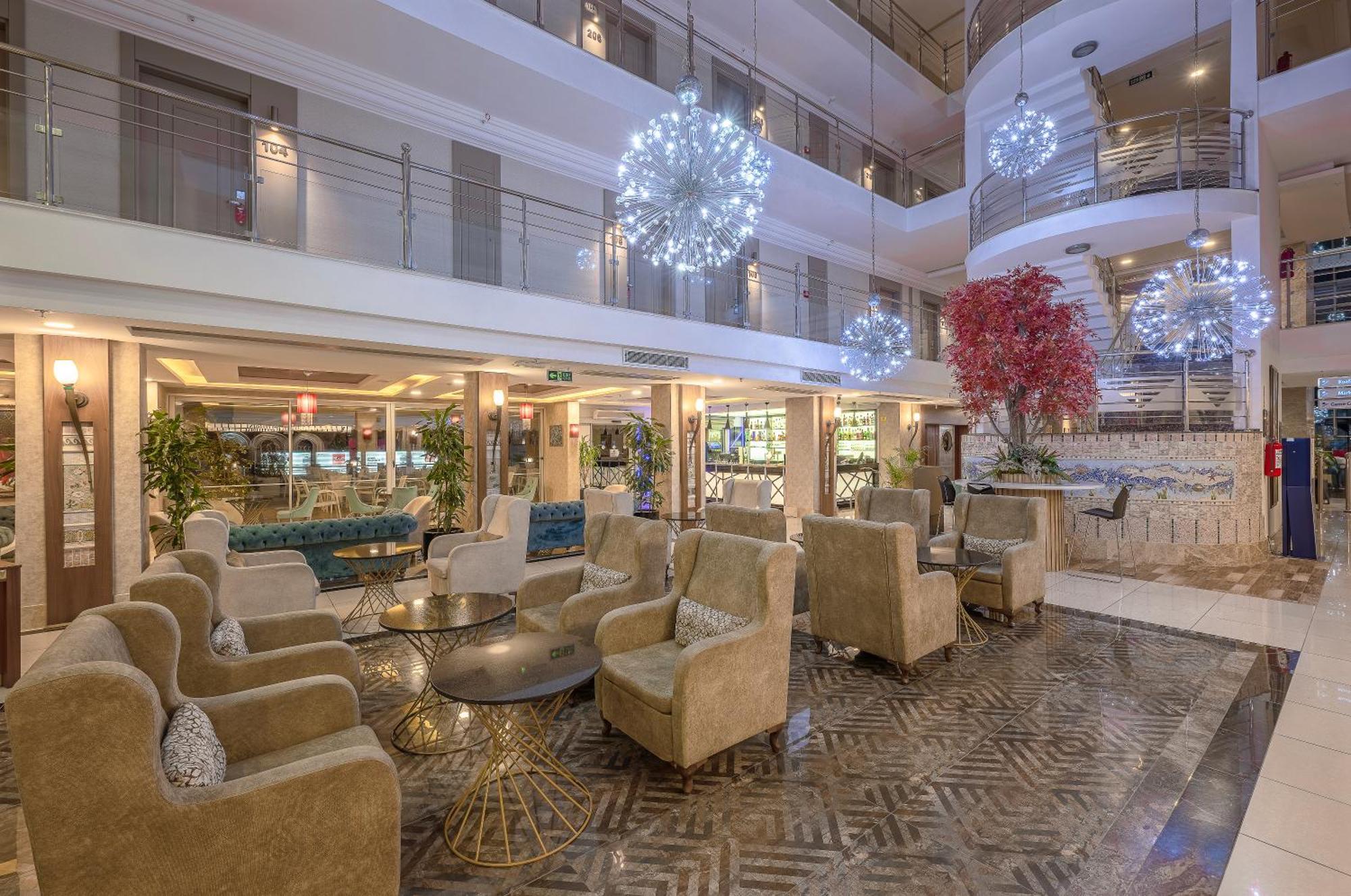 Sealife Family Resort Hotel Antalya Exterior foto The photo depicts a modern hotel lobby with a stylish and inviting atmosphere. It features a seating area furnished with plush, beige armchairs arranged around a round glass table. The floor boasts an elegant patterned design. 

In the background, th