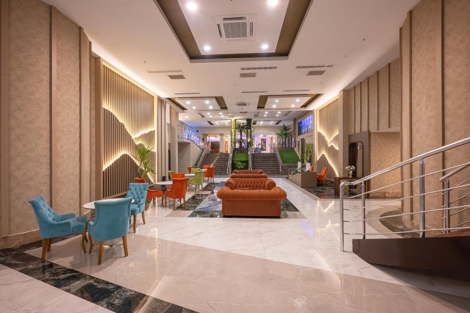 Sealife Family Resort Hotel Antalya Exterior foto The photo shows a modern lobby area of a hotel or building. The space is spacious, featuring a mix of lighting and decorative elements. There are elegant furnishings, including an orange sofa and colorful chairs in blue and orange. The floor is made 